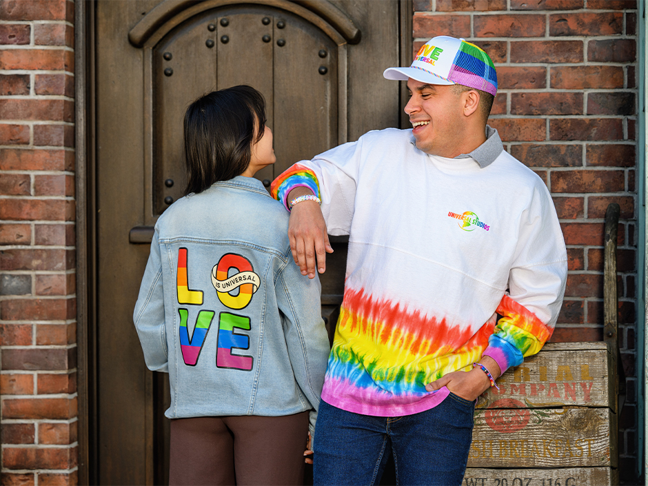 Two friends pose side by side in Love is Universal merchandise form Universal Orlando