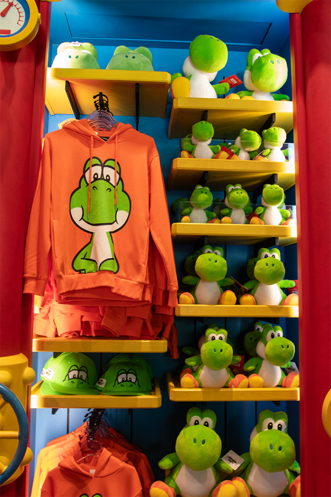 A variety of Yoshi merchandise, including plushes and hoodies.