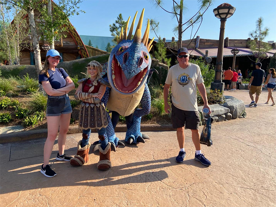 Kaitlyn and her dad pose for a photo with Astrid and Stormfly in Isle of Berk at Epic Universe
