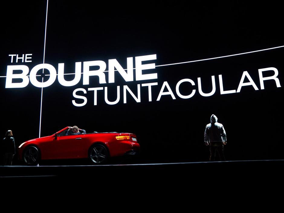 The opening scene of The Bourne Stuntacular at Unviersal Studios Florida, featuring Jason Bourne standing on stage next to a red sports car