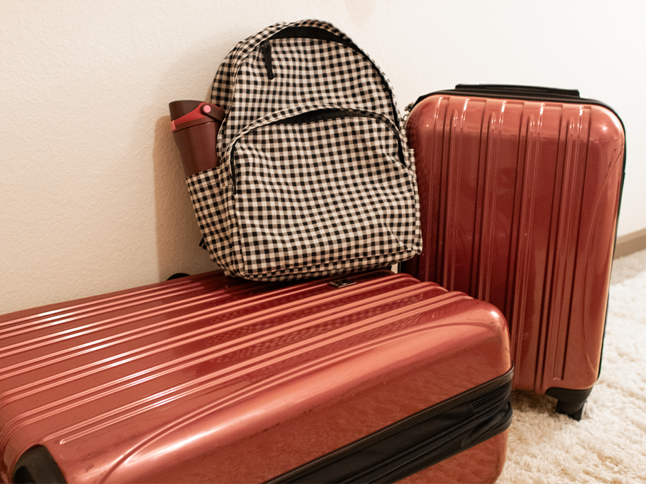 Two suitcases and a backpack against a white wall.