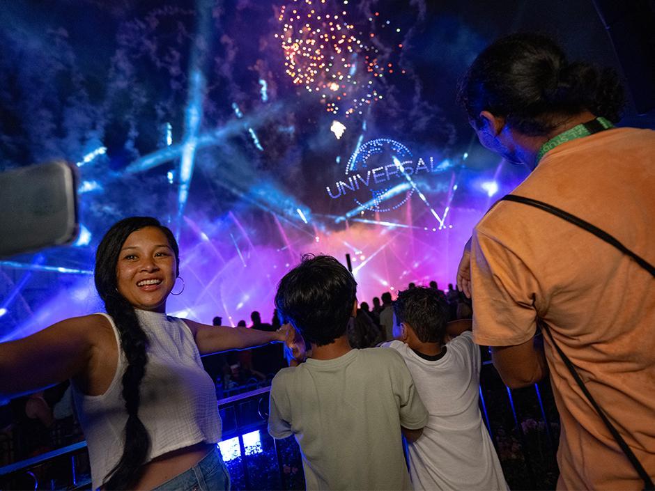 A mother takes a selfie with her kids in front of the Cinesational nighttime show