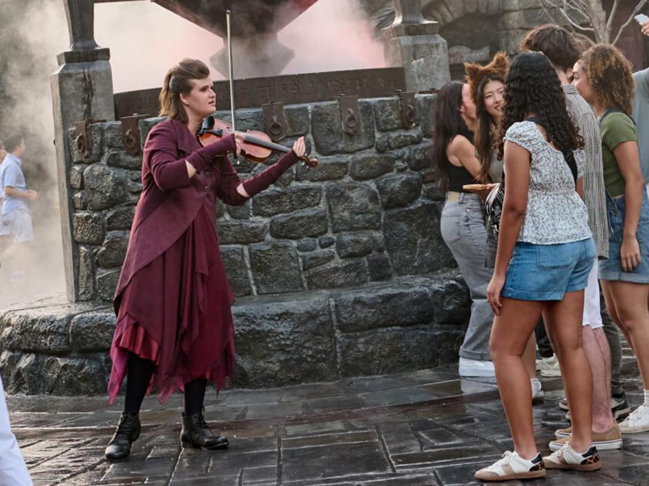 A violinist performs for guests in Dark Universe at Epic Universe