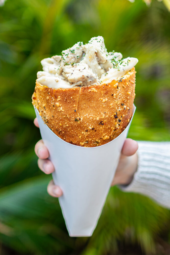 Hand holding a Chicken Alfredo Bread Cone in Jurassic Park at Universal Islands of Adventure.