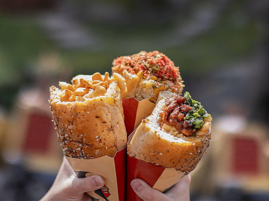 Hands holding three mac and cheese cones at Isle of Berk in Universal Epic Universe.