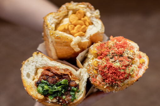 Hands holding three mac and cheese cones at Isle of Berk in Universal Epic Universe.