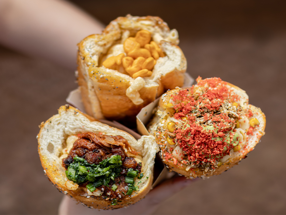 Hands holding three mac and cheese cones at Isle of Berk in Universal Epic Universe.