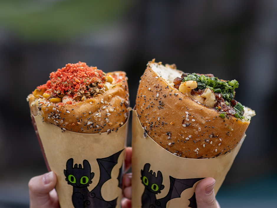 Hands holding two mac and cheese cones in Isle of Berk at Universal Epic Universe.