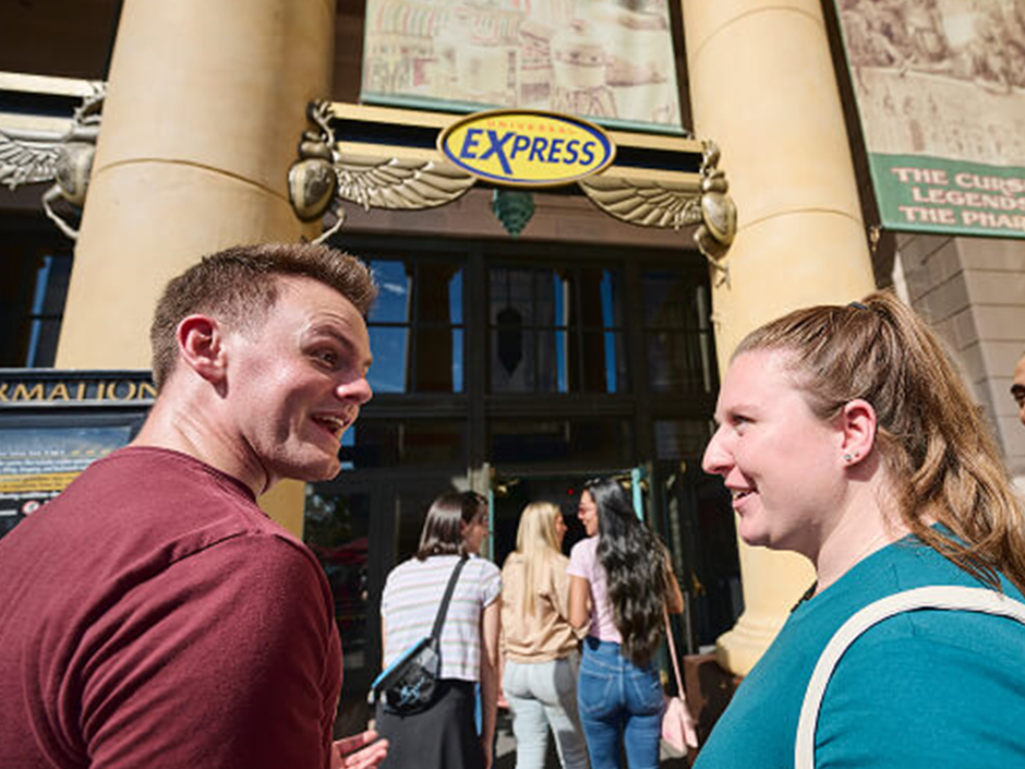 Two people smile at each other as they head into a Universal Express queue.
