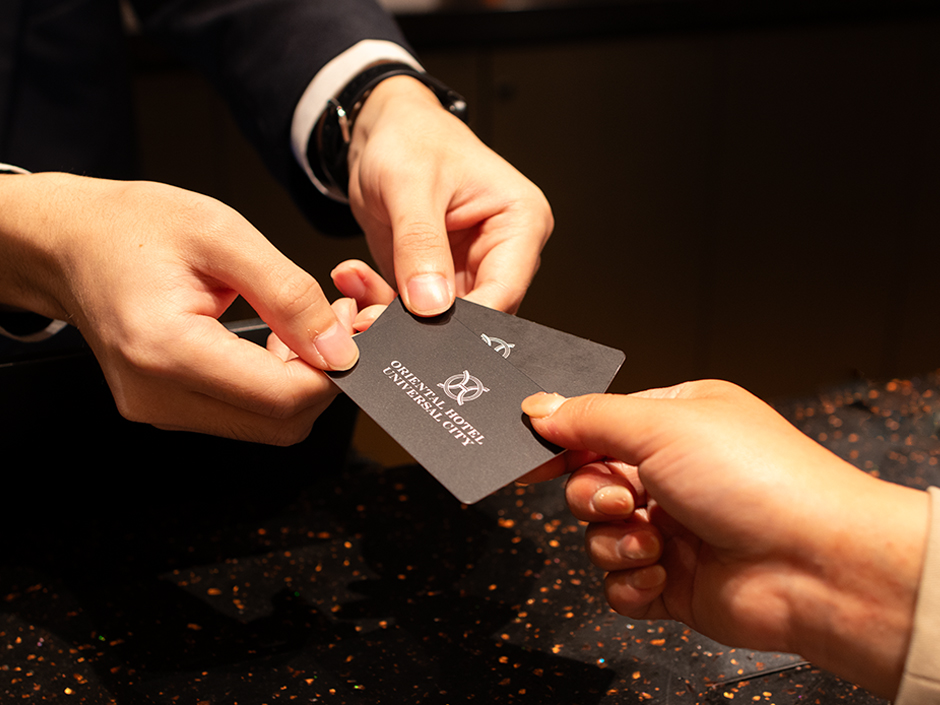 A person handing another person two hotel keys for the Oriental Hotel Universal City at Universal Studios Japan