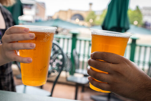 Hands holding cups of Dufftoberfest Beer at Duff Gardens in Springfield U.S.A. at Universal Studios Florida.