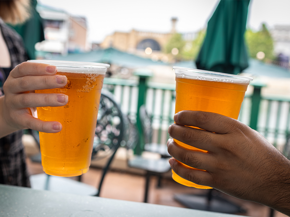 Hands holding cups of Dufftoberfest Beer at Duff Gardens in Springfield U.S.A. at Universal Studios Florida.
