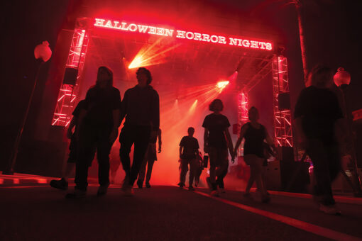 Silhouettes of guests walking through the Halloween Horror Nights entrance in neon lights at HHN