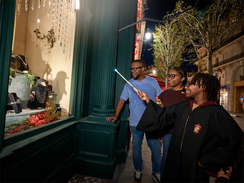 A little boy casts spells with his family as his family watches in The Wizarding World of Harry Potter - Ministry of Magic 