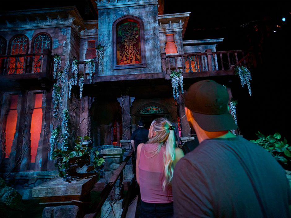 A line of guests walks toward the facade of a haunted house at Universal Halloween Horror Nights