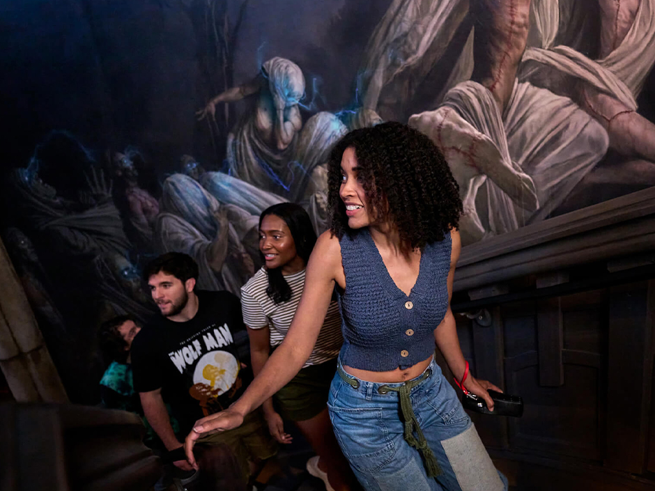 Three guests smile at each other as they walk through the staircase area of the Monsters Unchained: The Frankenstein Experiment queue