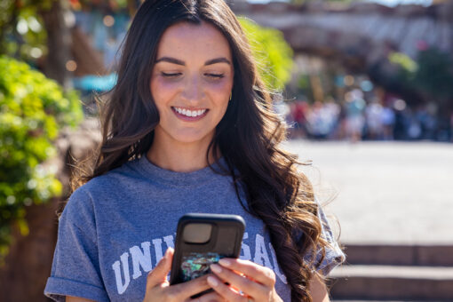 A girl smiles at her phone inside Islands of Adventure