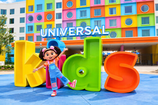 Doozie from "Doozie's Doghouse" poses in front of the Universal Kids Resort marquee.